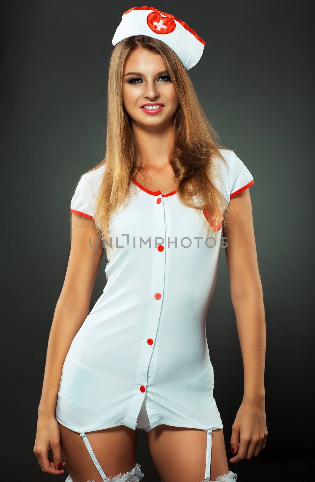 Young and beautiful dancer in nurse costume posing on studio background