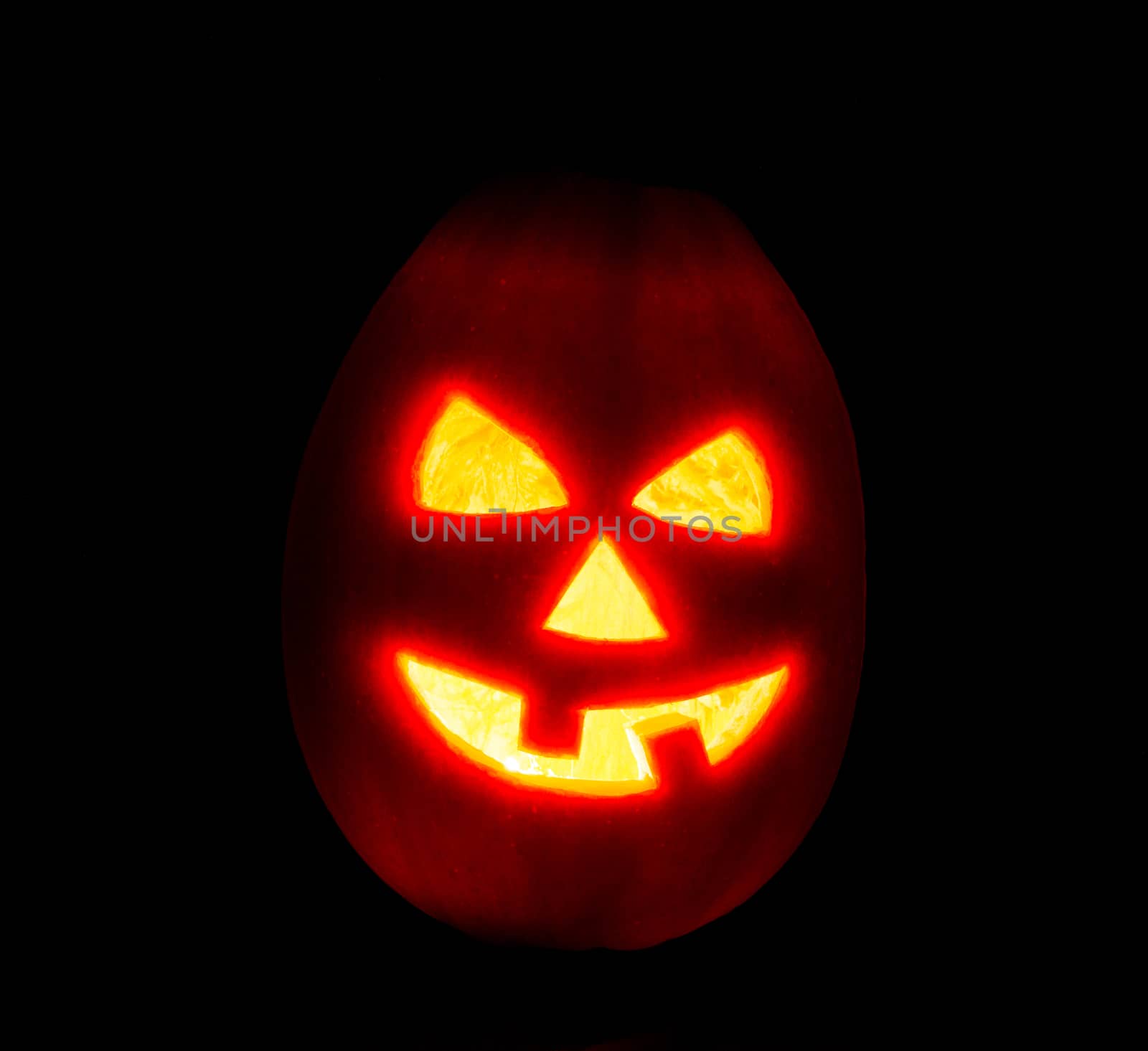 Halloween pumpkin jack-o-lantern candle lit, isolated on black background