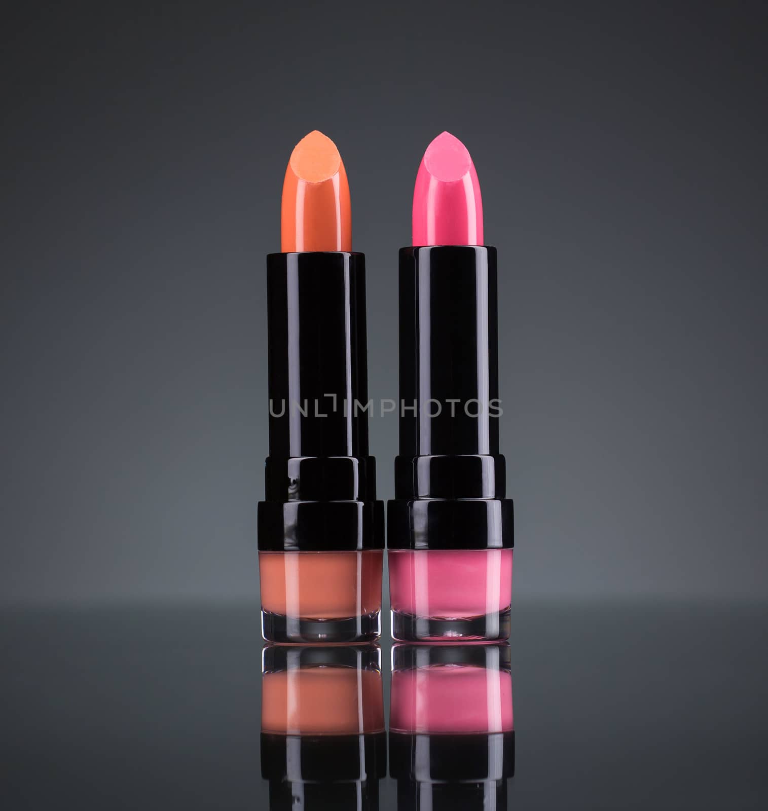 Two bright lipsticks on a black background