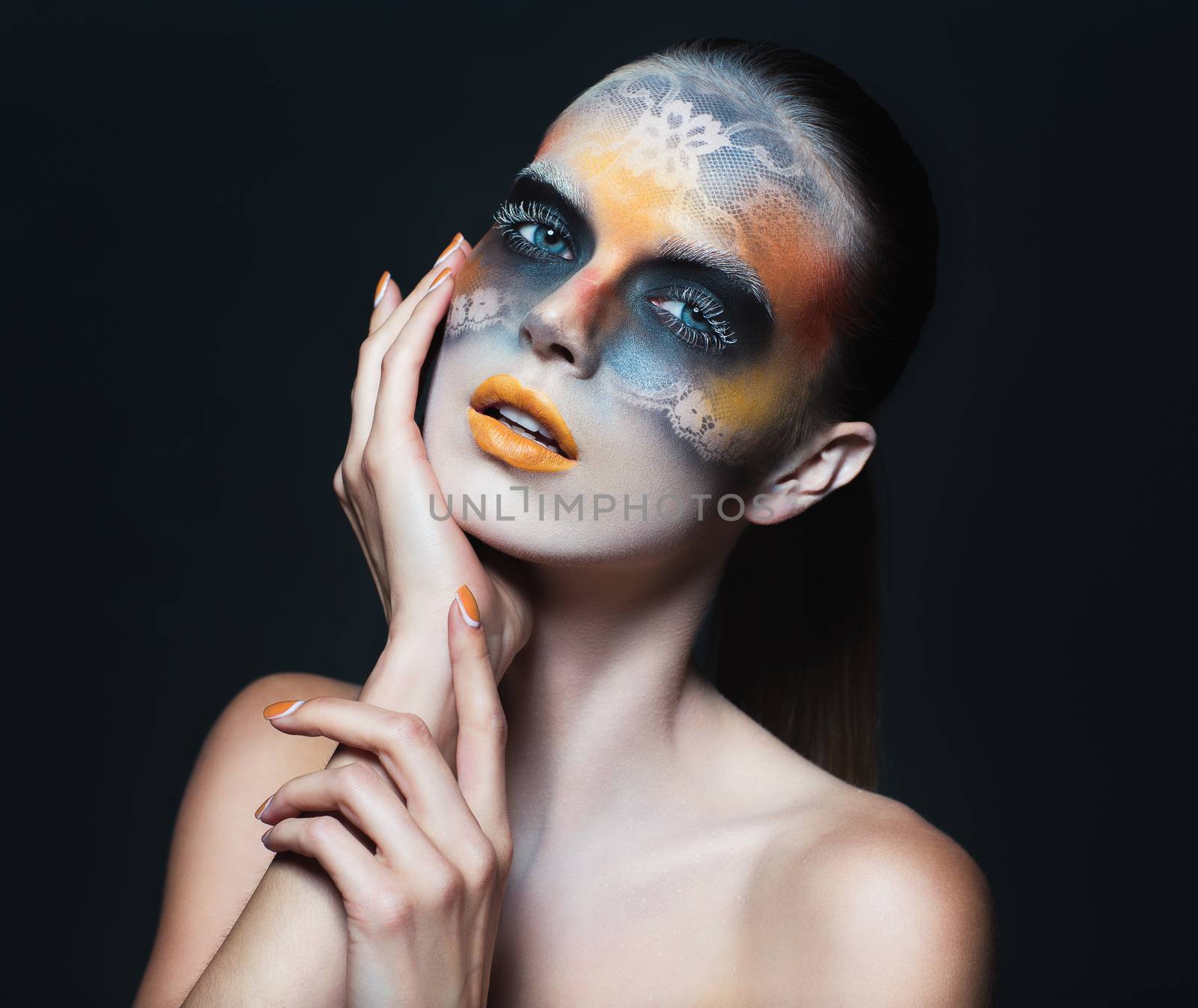 Portrait of beautiful glamor girl with dark eye make-up in the form of lace and orange lips on black