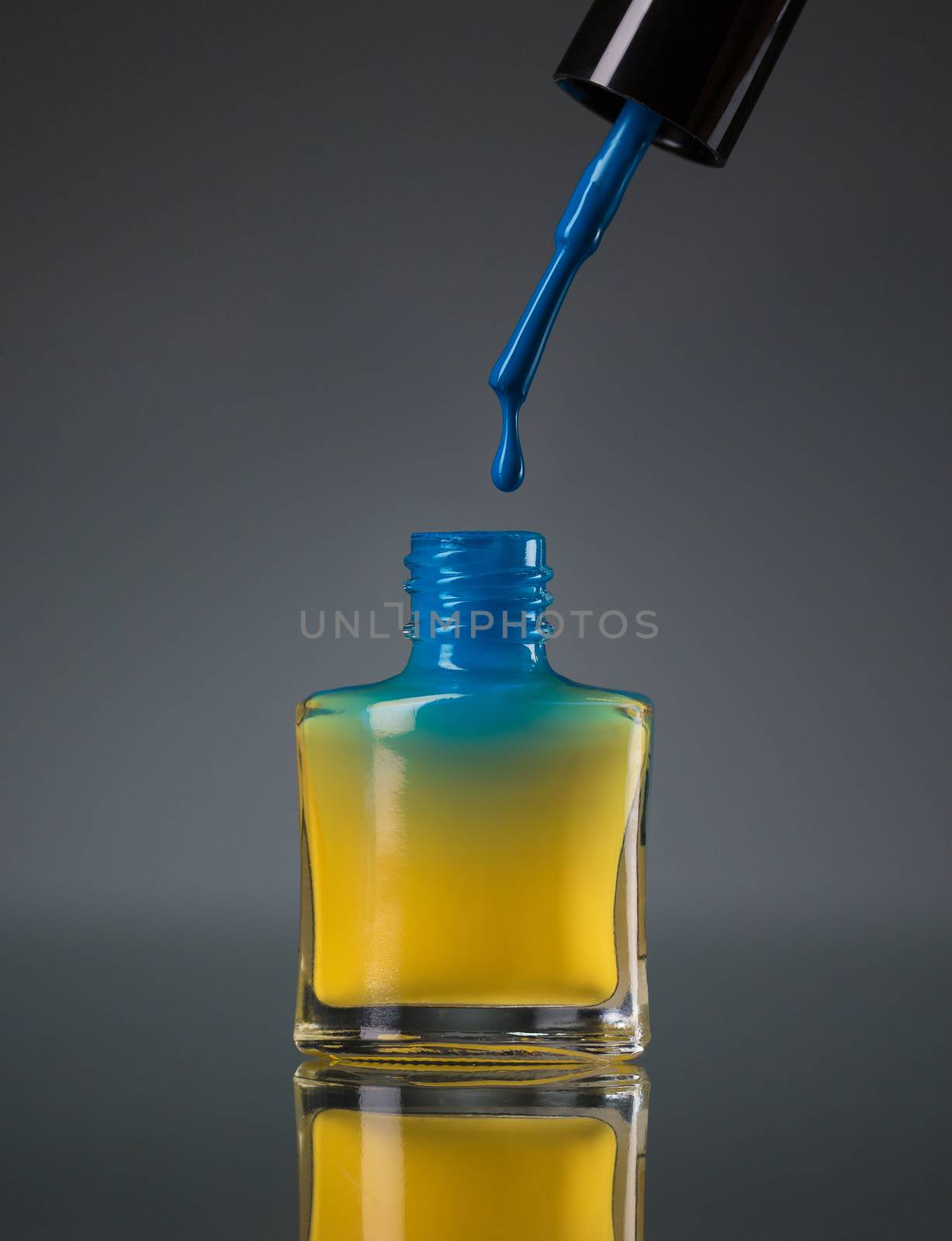 Flowing blue nail polish in a yellow bottle isolated on black by vlad_star