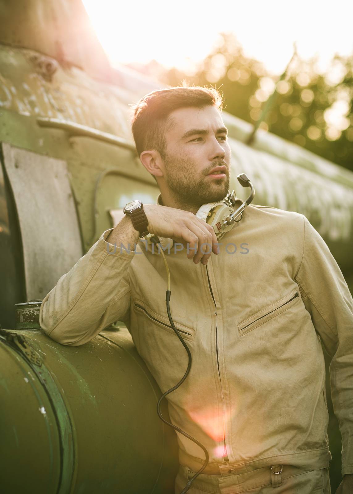 Young serious pilot posing near the helicopter