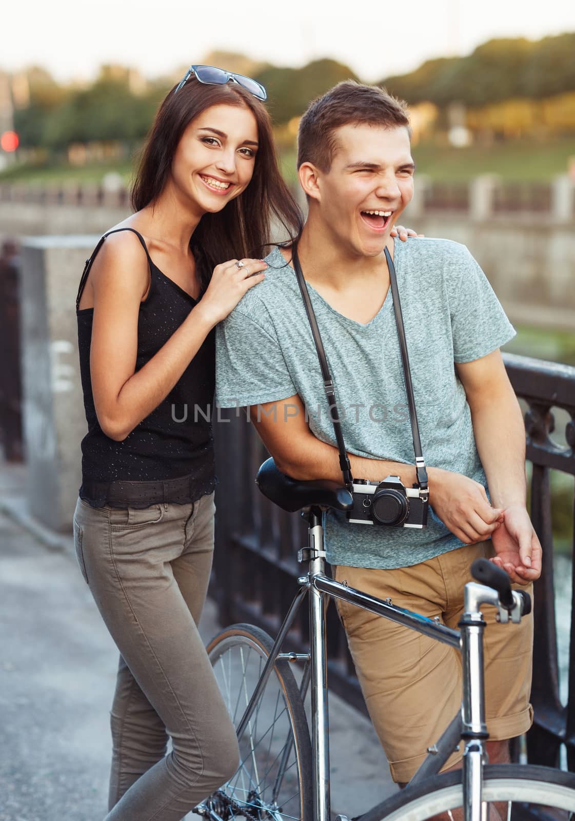 Happy couple - young smiling man and woman with bike in the park outdoor