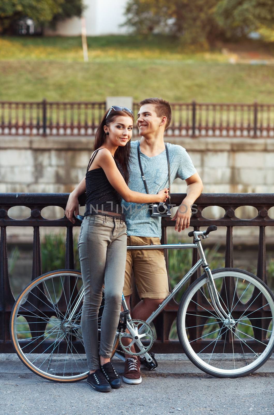 Happy couple - young smiling man and woman with bike in the park outdoor