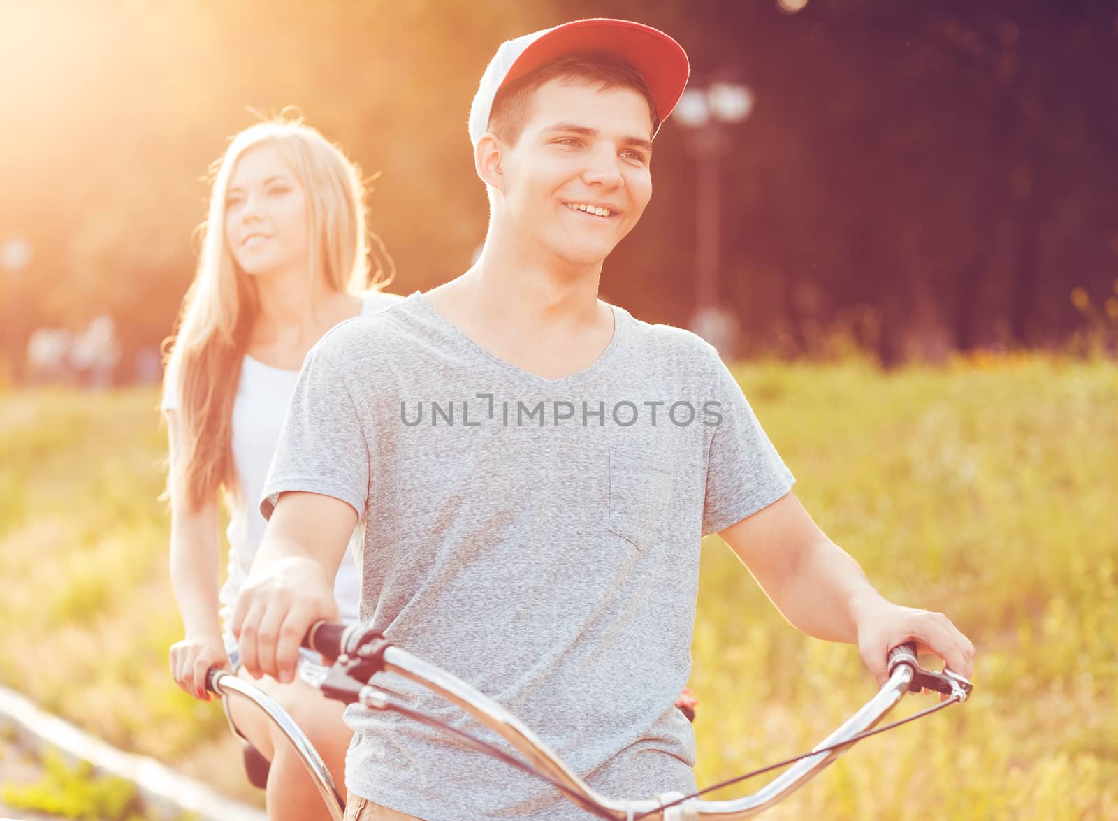 Happy couple - man and woman riding a bicycle in the park outdoo by vlad_star