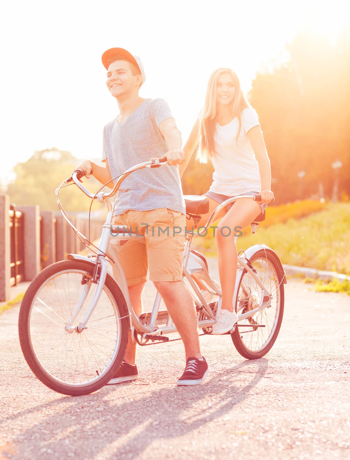 Happy couple - man and woman riding a bicycle in the city street