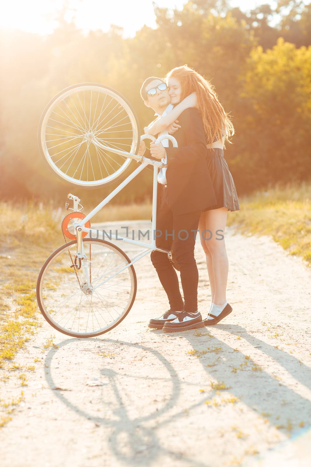 Young stylish couple - the guy with the girl and bicycle outdoors