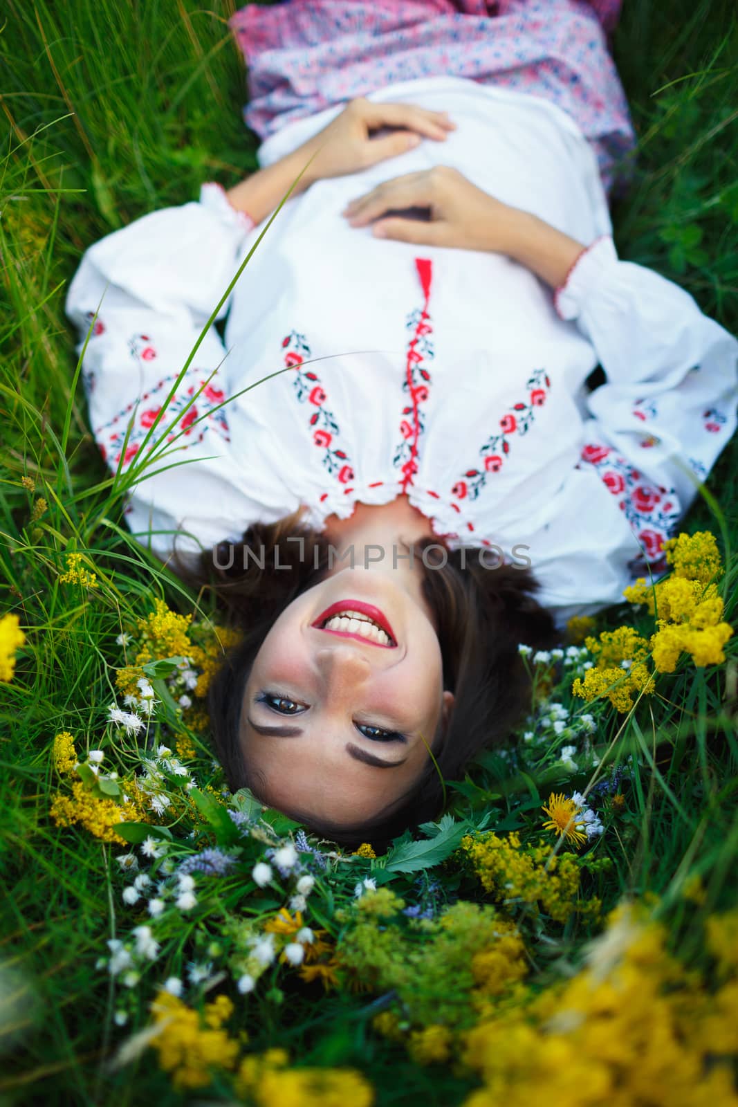 Young beautiful smiling girl in Ukrainian costume with a wreath on his head in a meadow