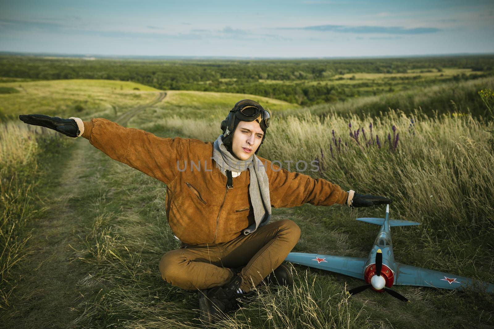 Young guy in vintage clothes pilot with an airplane model outdoors