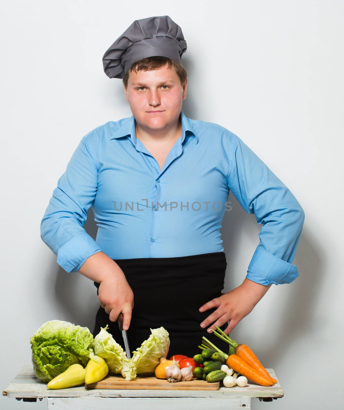 Plump cook on gray wall background