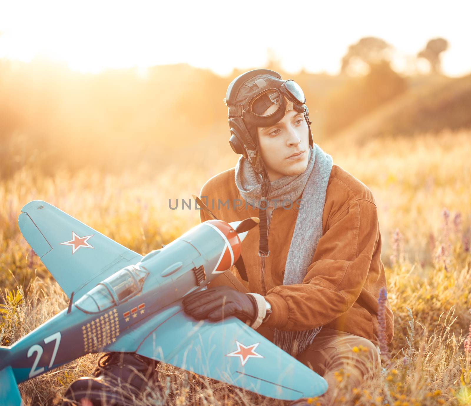 Young guy in vintage clothes pilot with an airplane model outdoors