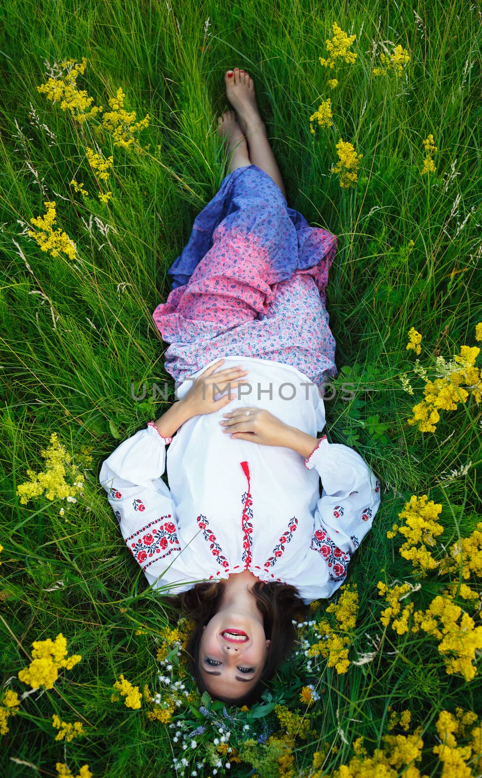 Young beautiful smiling girl in Ukrainian costume with a wreath on his head in a meadow