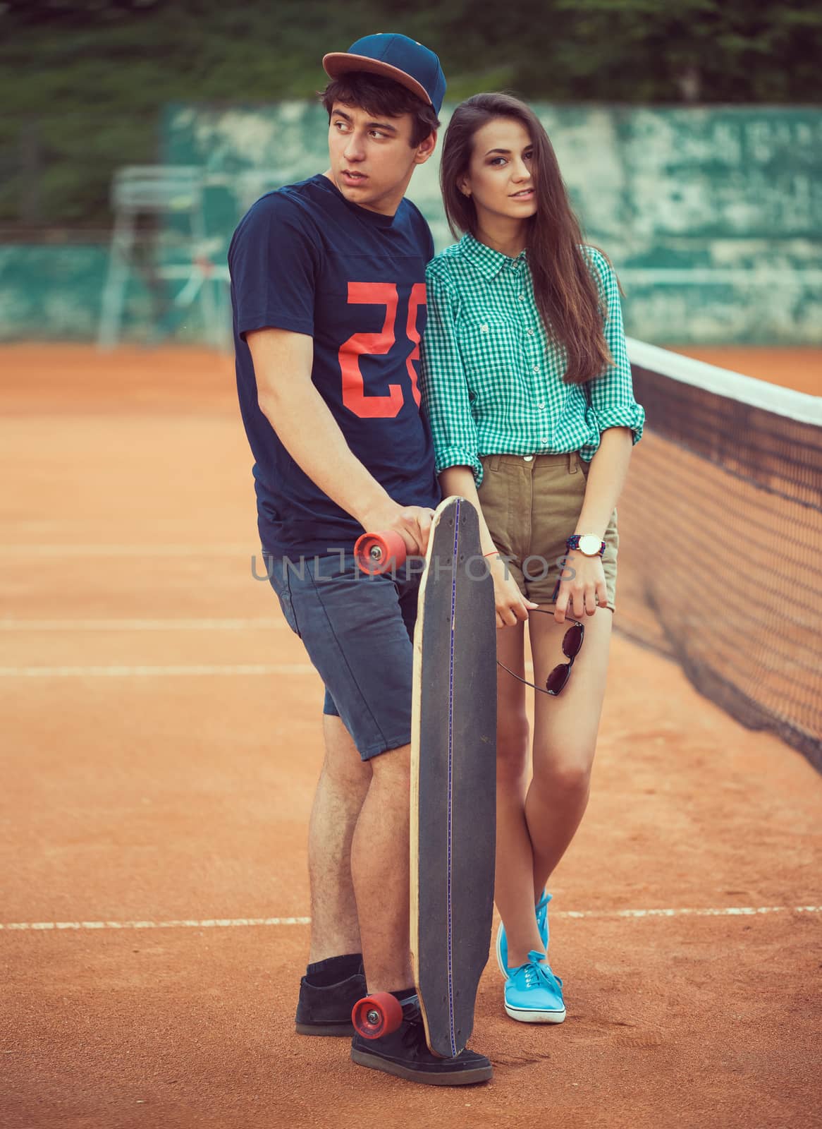 Young couple standing on a skateboard on the tennis court by vlad_star