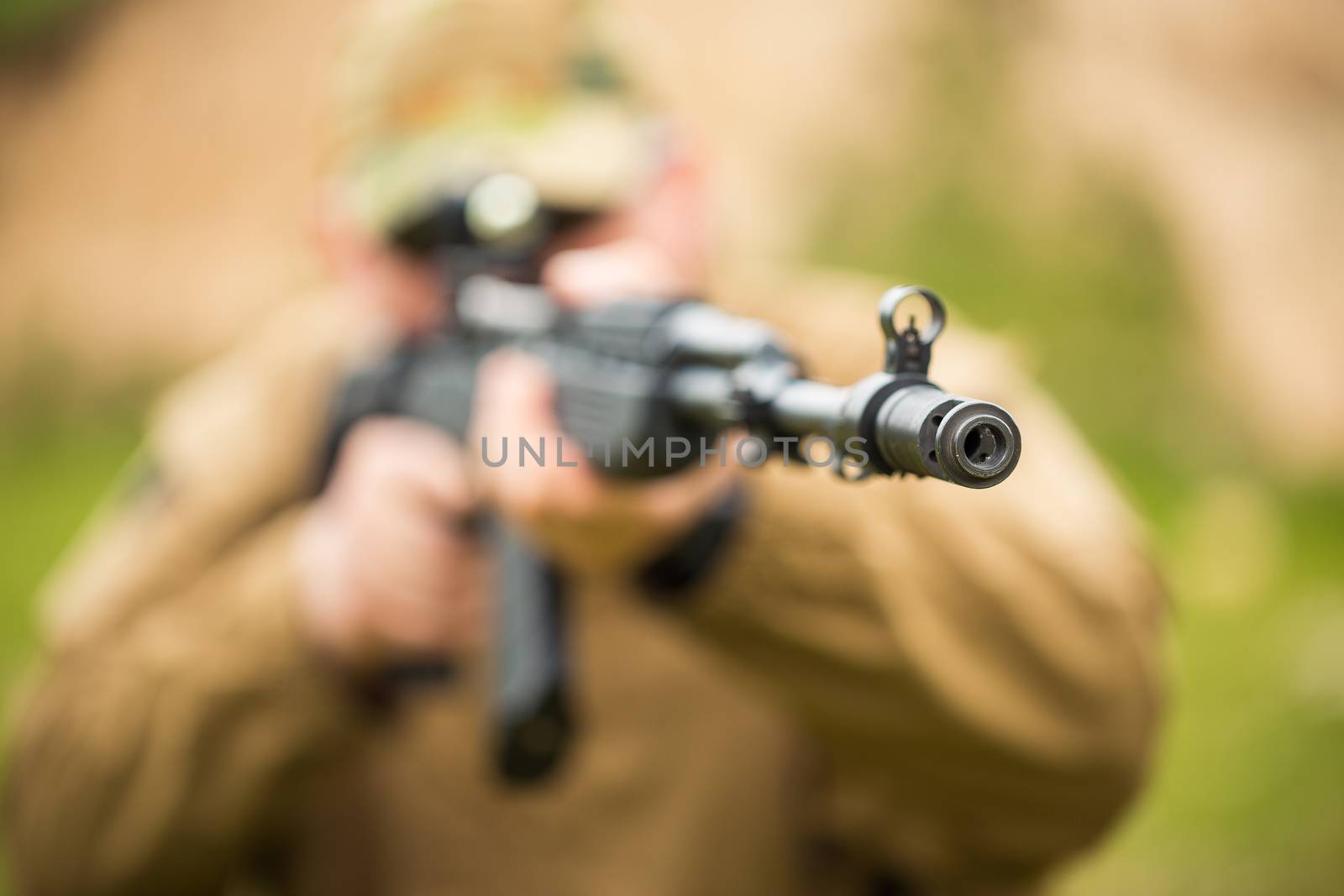 Man in camouflage with a shotgun aiming at a target. Focus on hole, small DOF