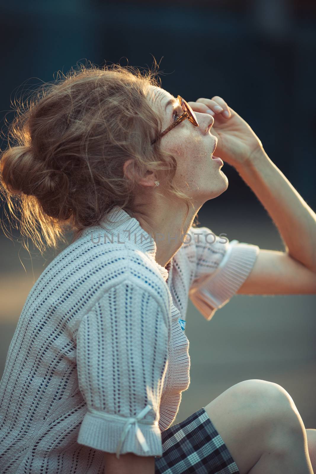 Funny girl student with glasses and a vintage dress sitting outdoors