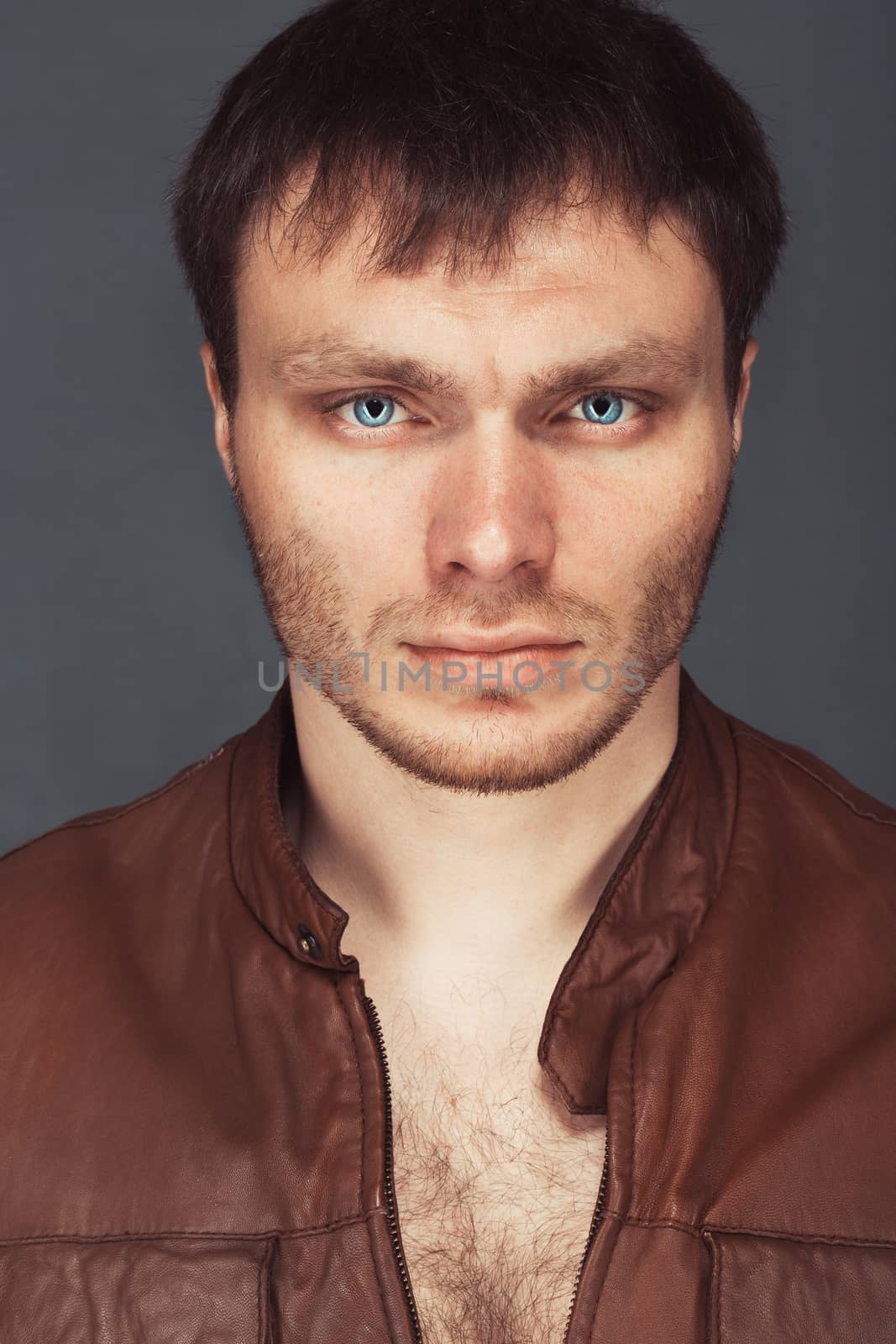 Portrait of a smart serious young man standing against dark background