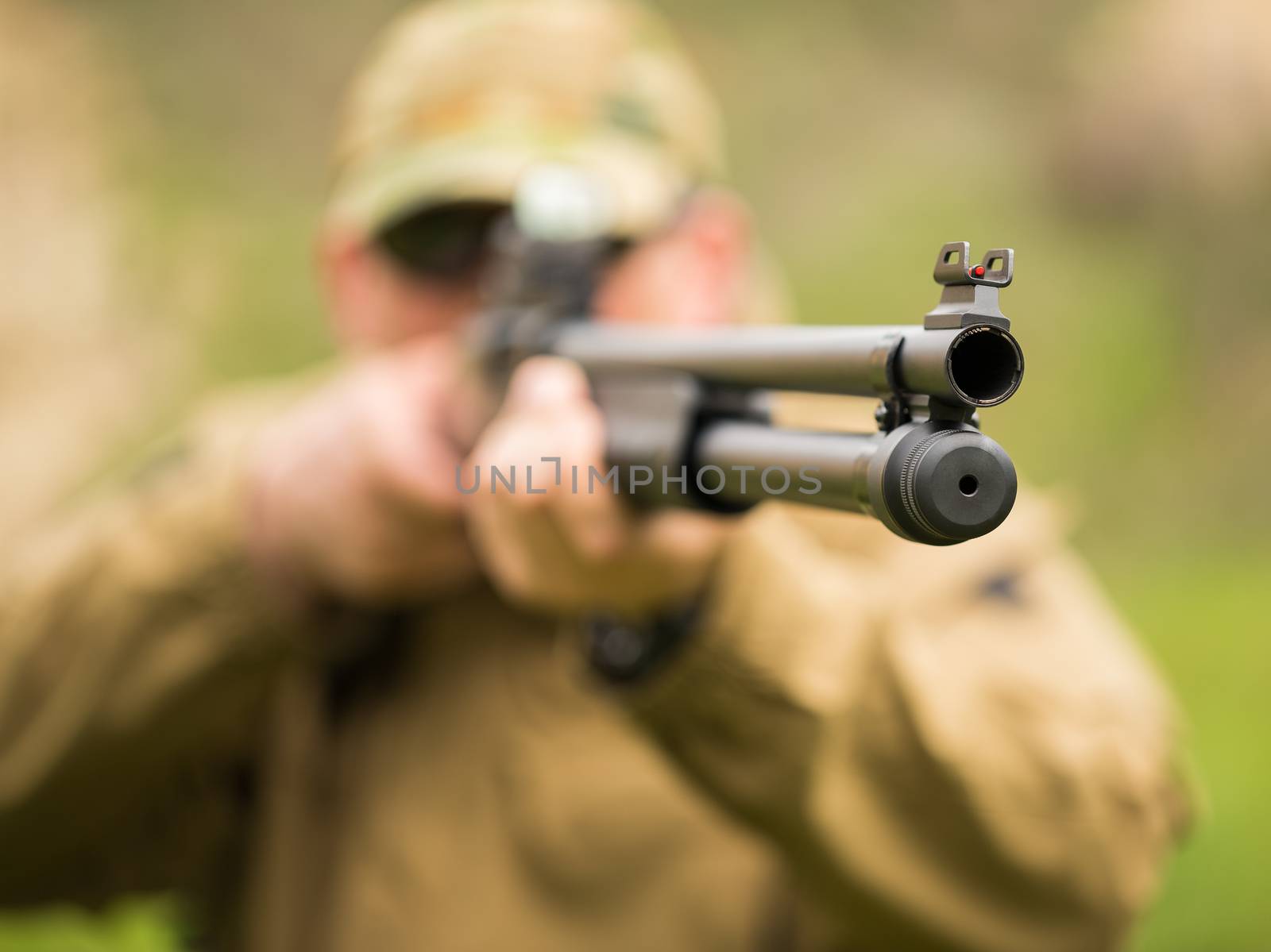 Man in camouflage with a shotgun aiming at a target. Focus on tvole, small DOF