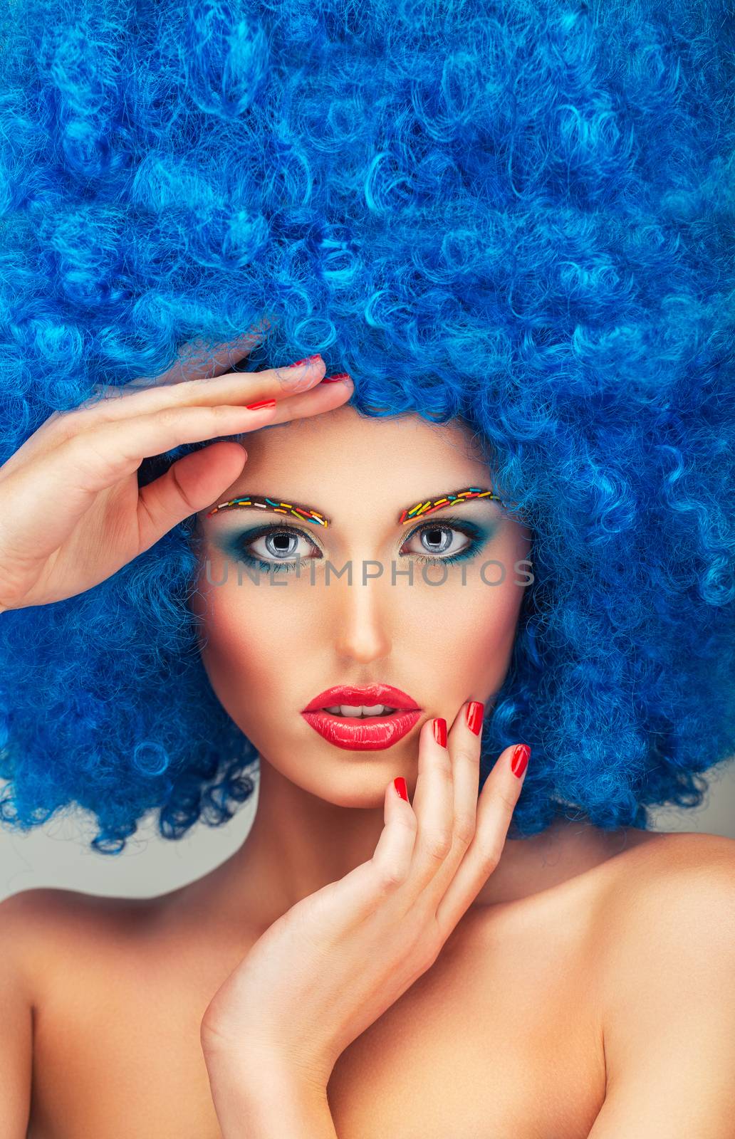 Portrait of a young beautiful girl with bright makeup, red lips in blue wig