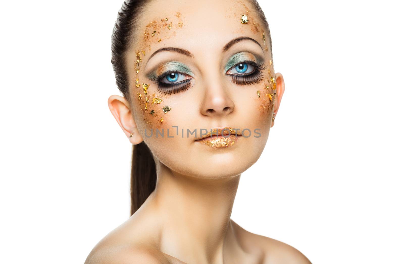 Glamorous portrait of young beautiful girl with big blue eyes, lush lashes and bright golden makeup. Fashion shiny highlighter on skin, velvet skin, gold lips