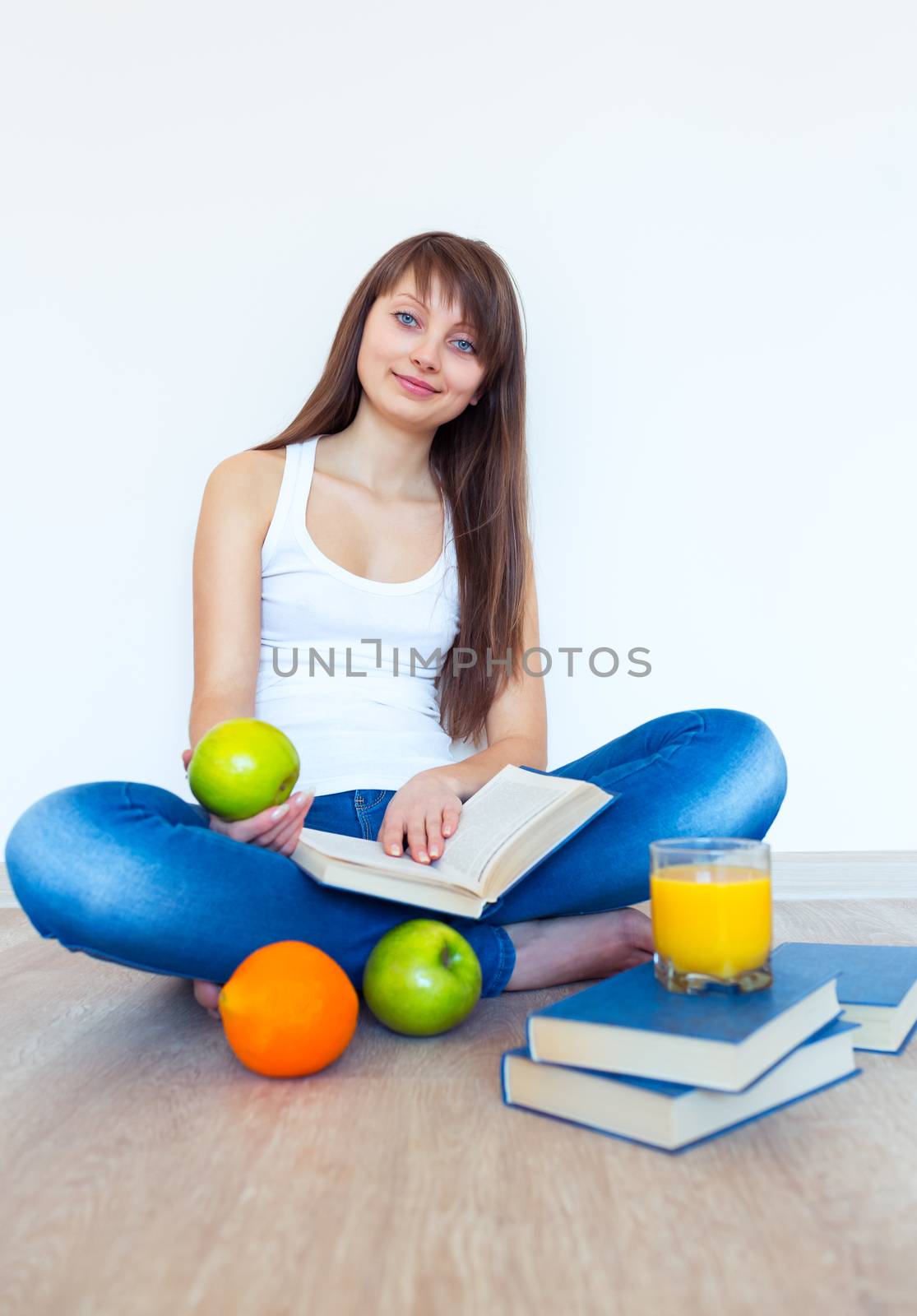 Young caucasian brunette with apple reading a book at home