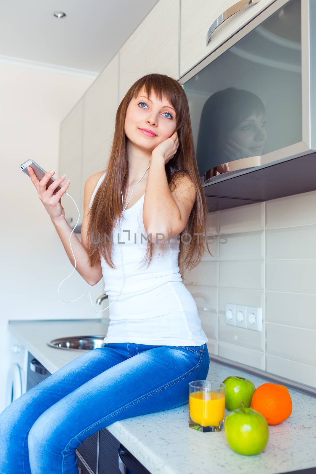 Young girl in the kitchen listening to music on headphones by vlad_star