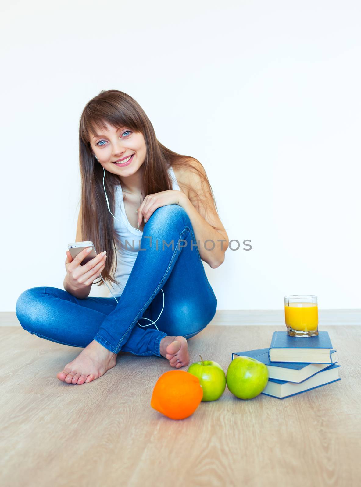 Portrait of a young girl with headphones and green apple listening music at home