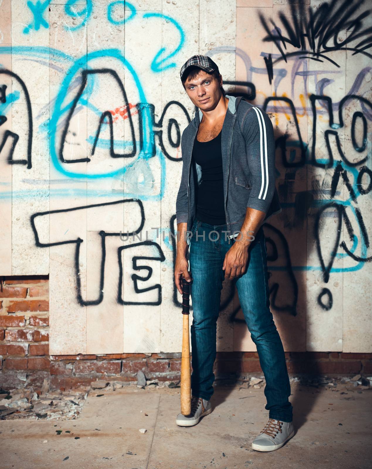 Muscular man with baseball bat on the ruins