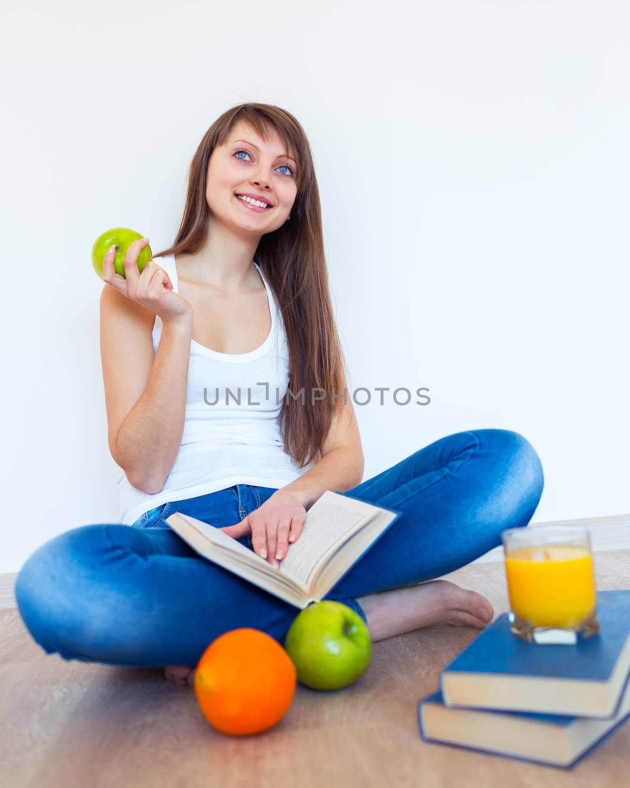 Young caucasian brunette with apple reading a book at home