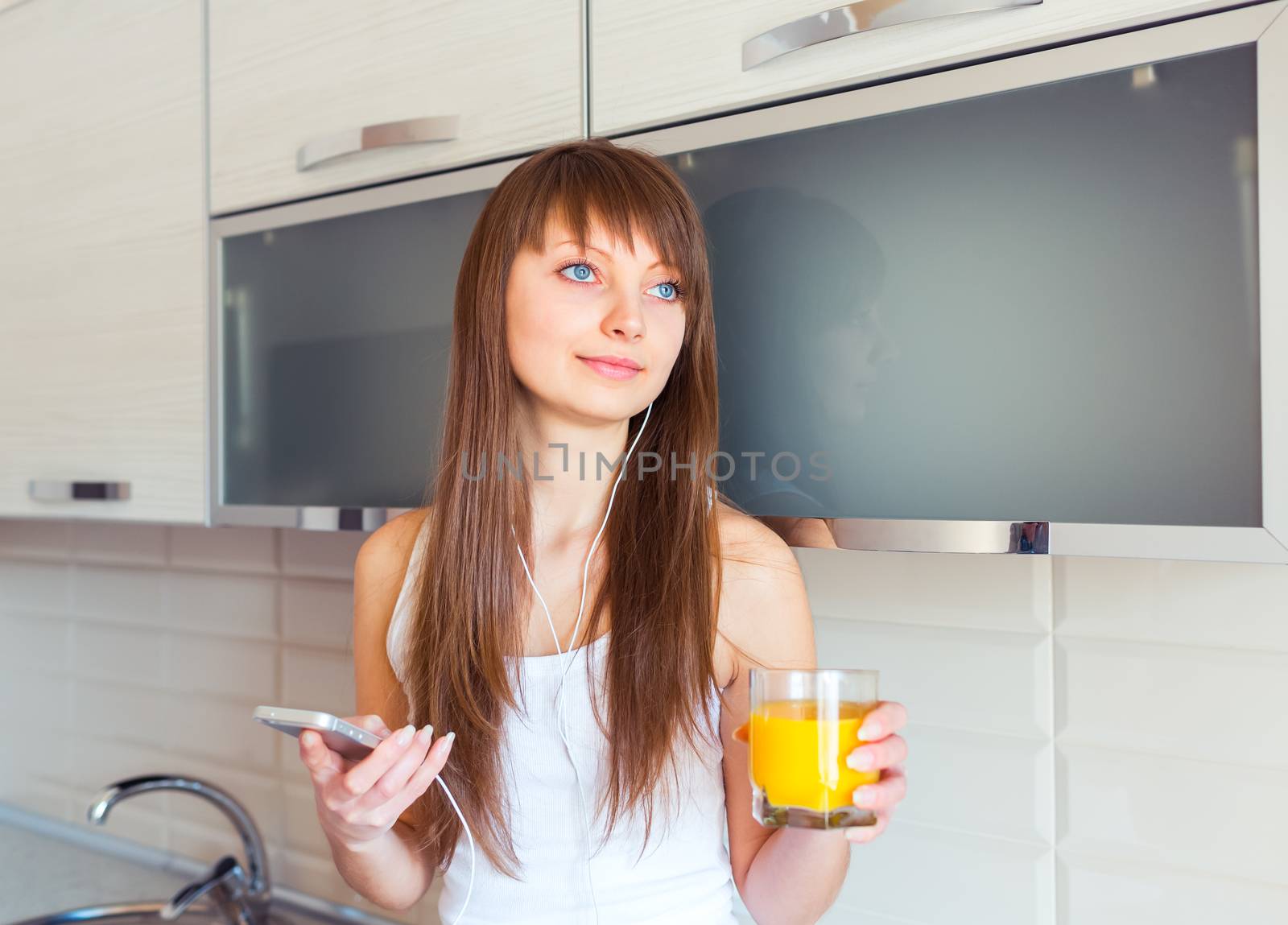 Young woman in the kitchen listening to music on headphones