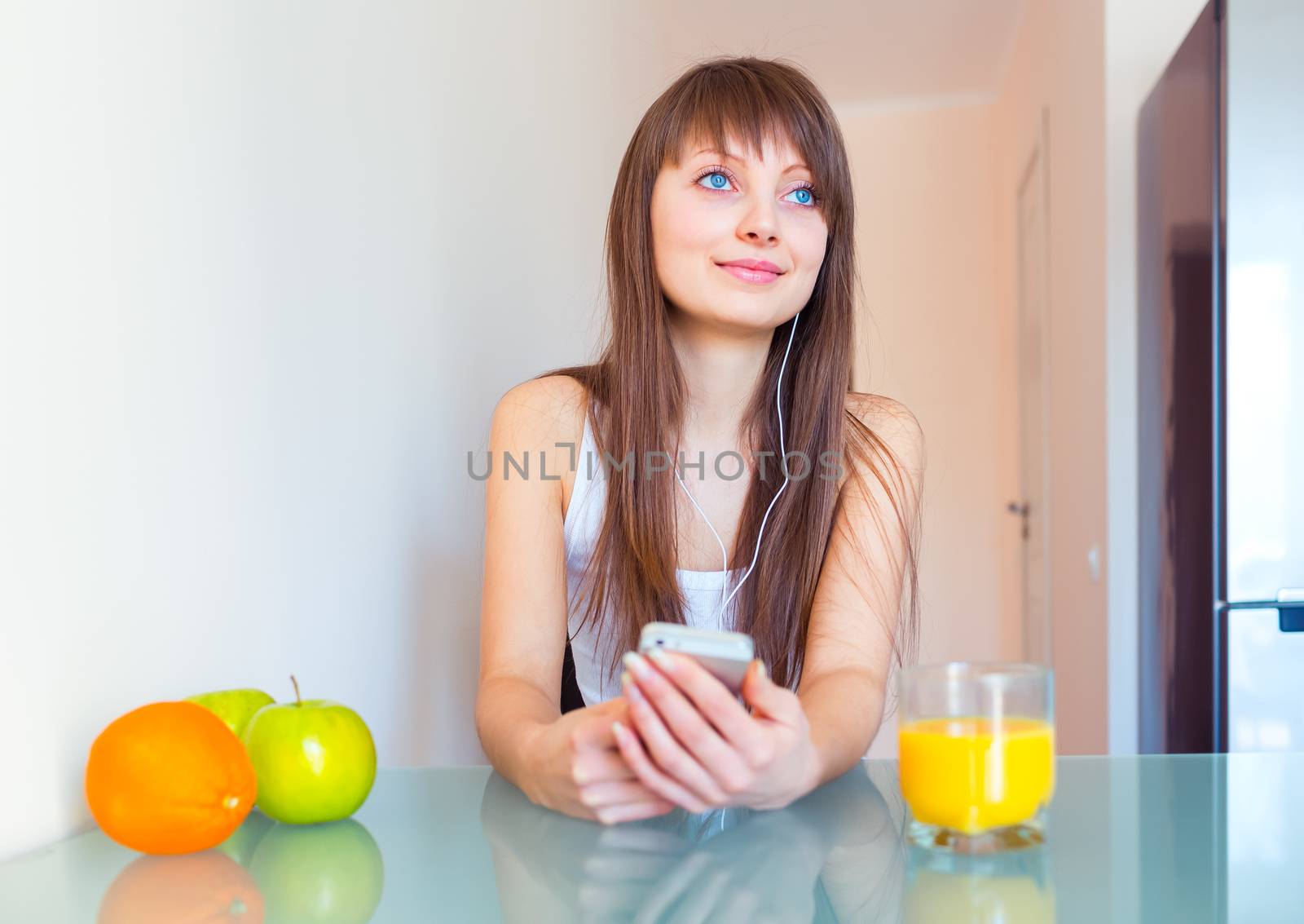 Young woman in the kitchen listening to music on headphones