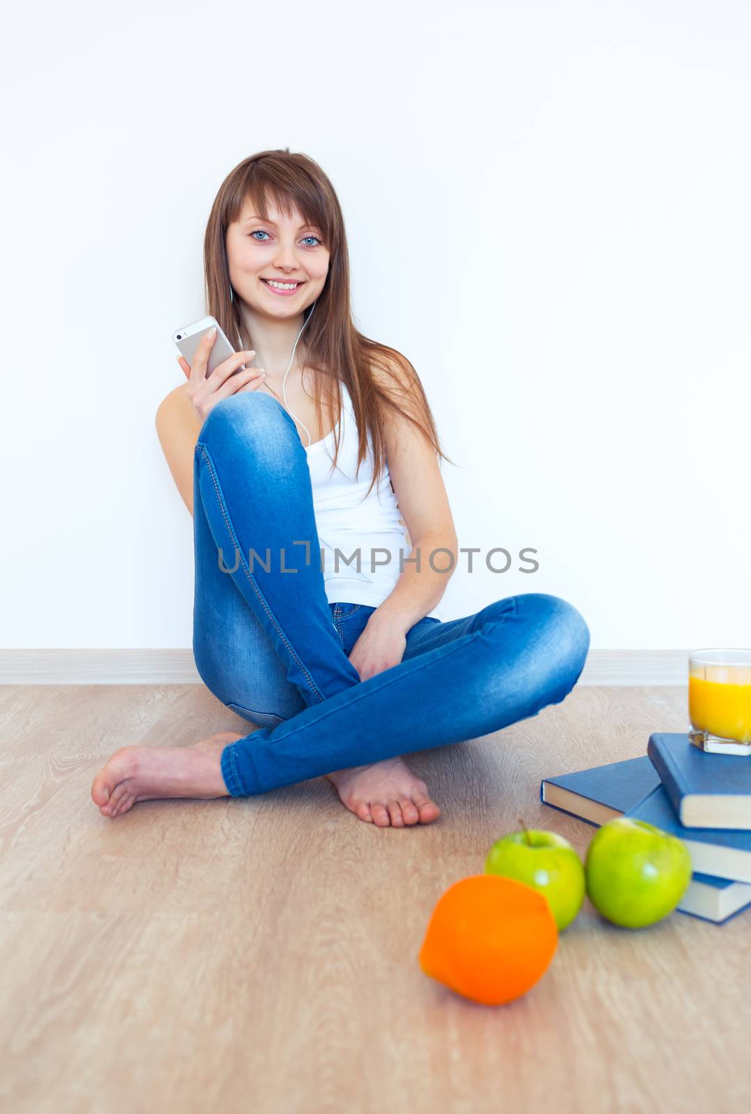 Portrait of a young woman with headphones and green apple listening music at home