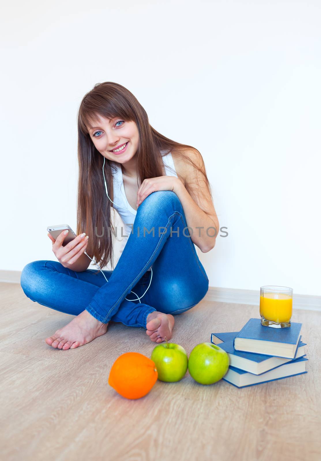 Portrait of a young woman with headphones and green apple listening music at home