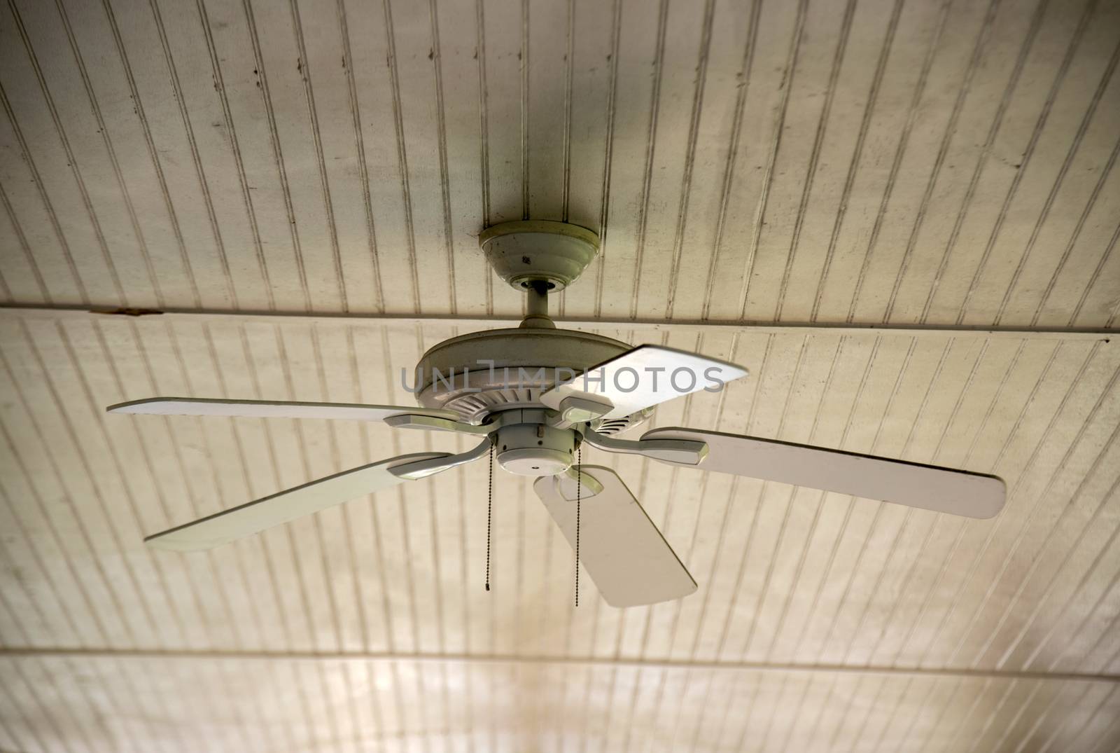 An old ceiling fan against a wooden siding