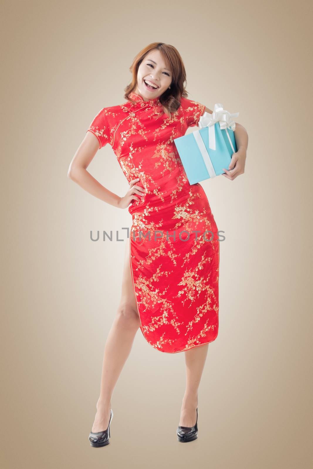 Smiling Chinese woman dress traditional cheongsam standing and holding a gift box at New Year, full length portrait isolated.