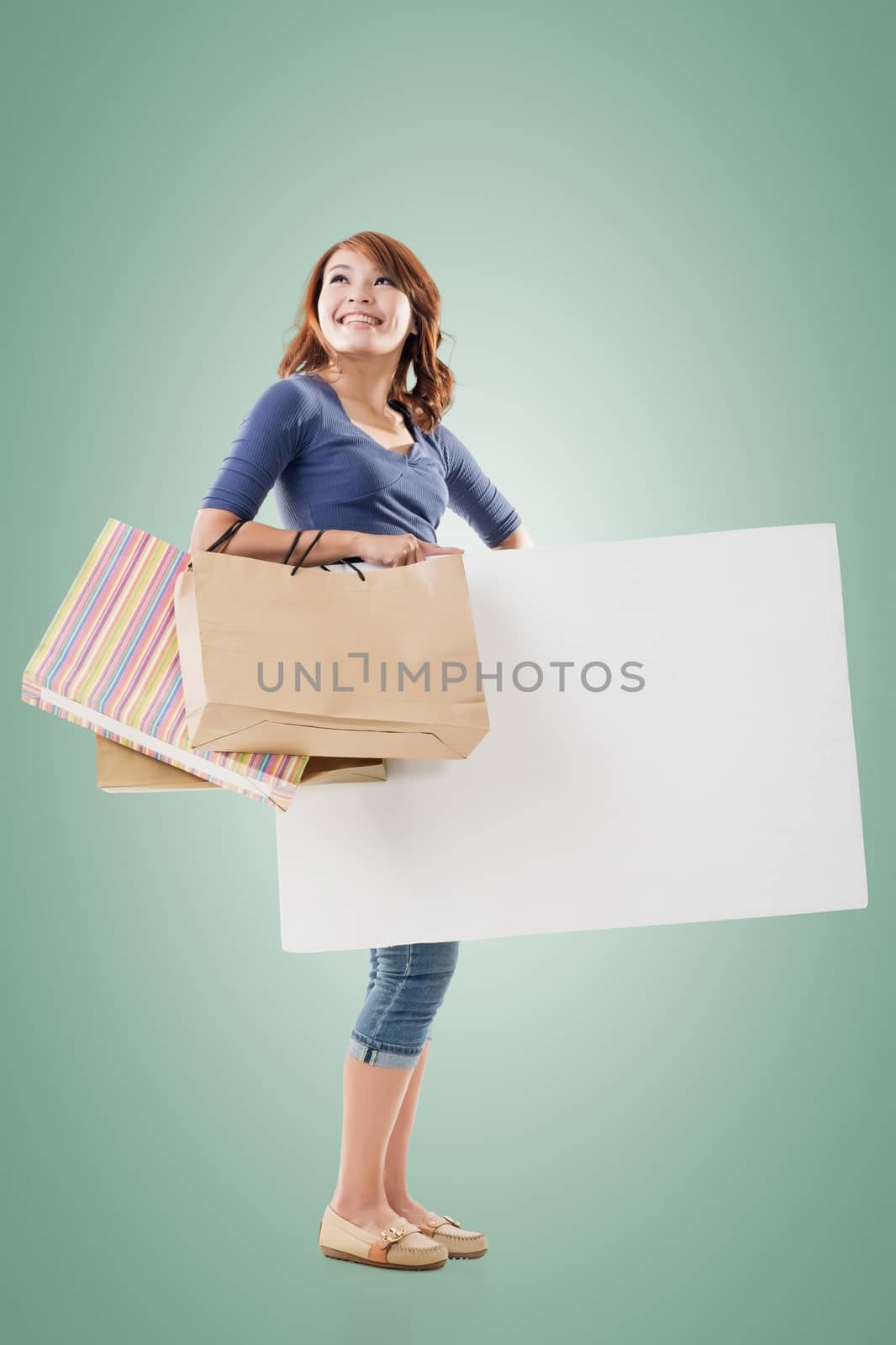 Shopping woman holding bags and blank board, full length portrait isolated.