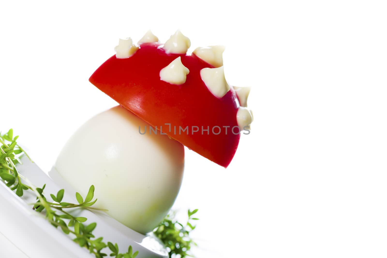 Funny food - boiled egg, cover with a tomato with mayonnaise points on leek bed