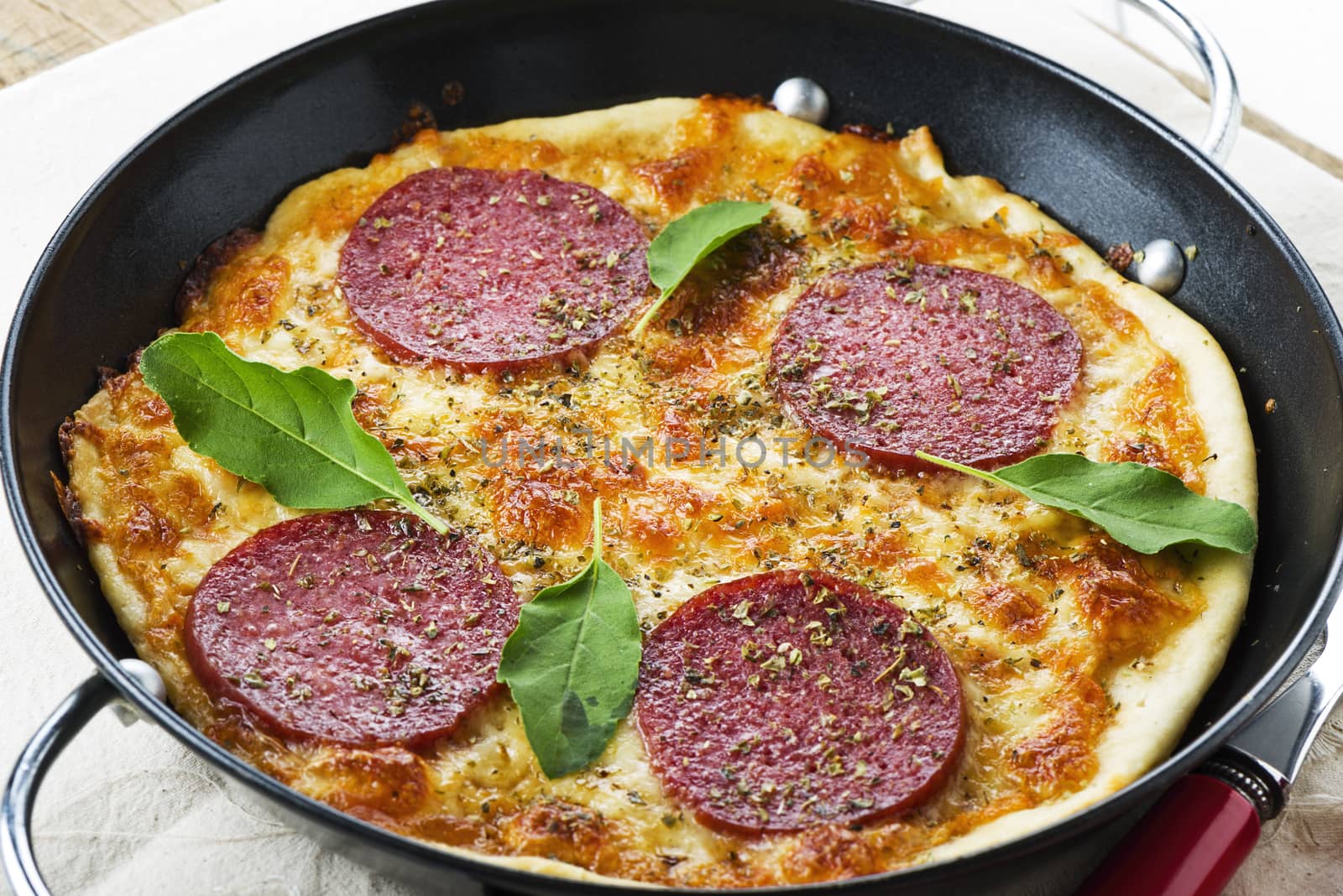 closeup of a mini salami pizza in a small black pan