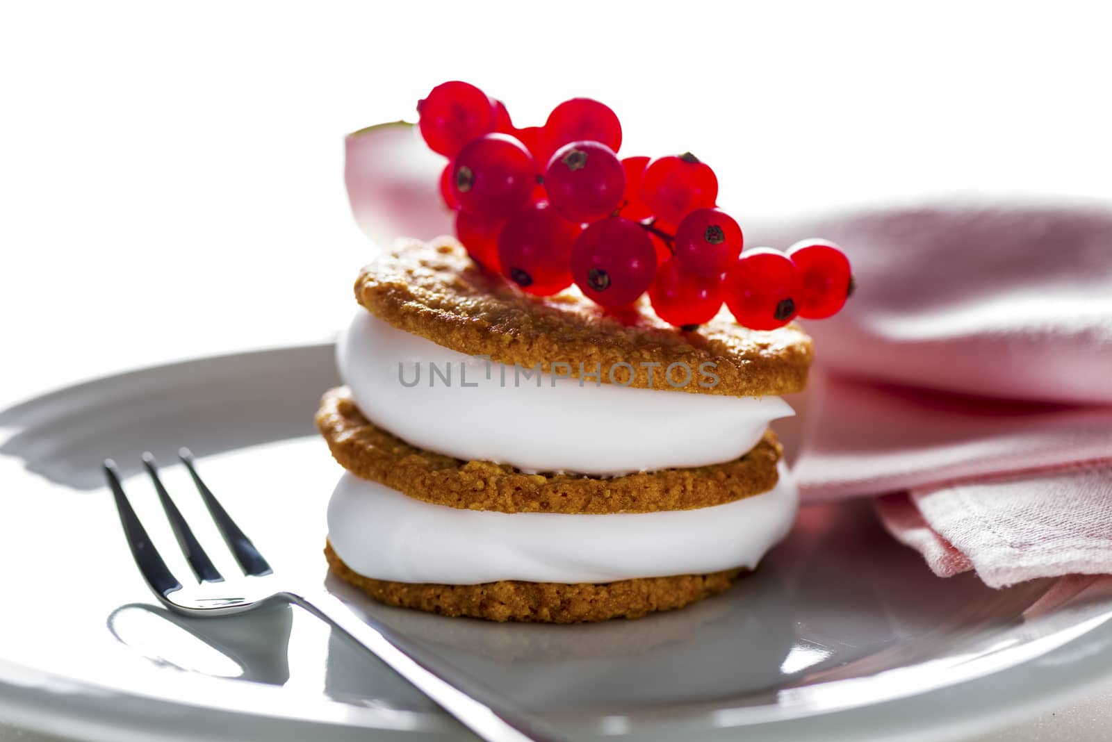 small cake with cream topping with currant on white plate