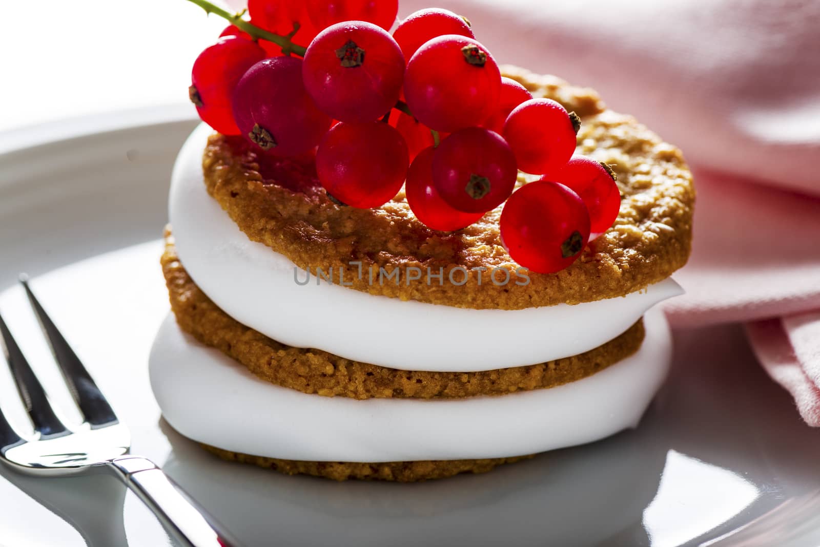 small cake with cream topping with currant on white plate