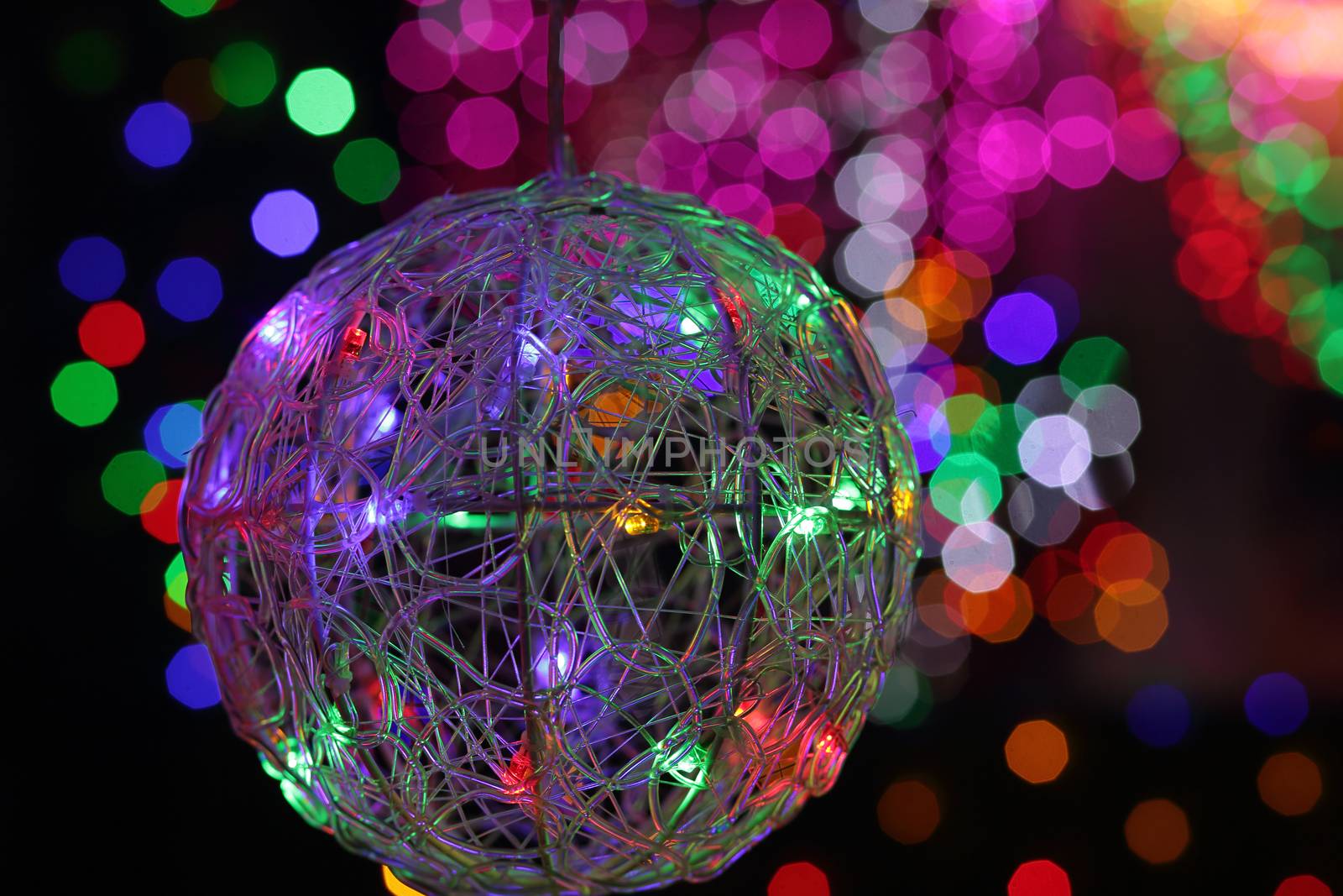 BEAUMONT HILLS, AUSTRALIA - DECEMBER 24, 2015;  Christmas wire mesh bauble ball in foreground with defocused colorued led lights in background - bokeh
