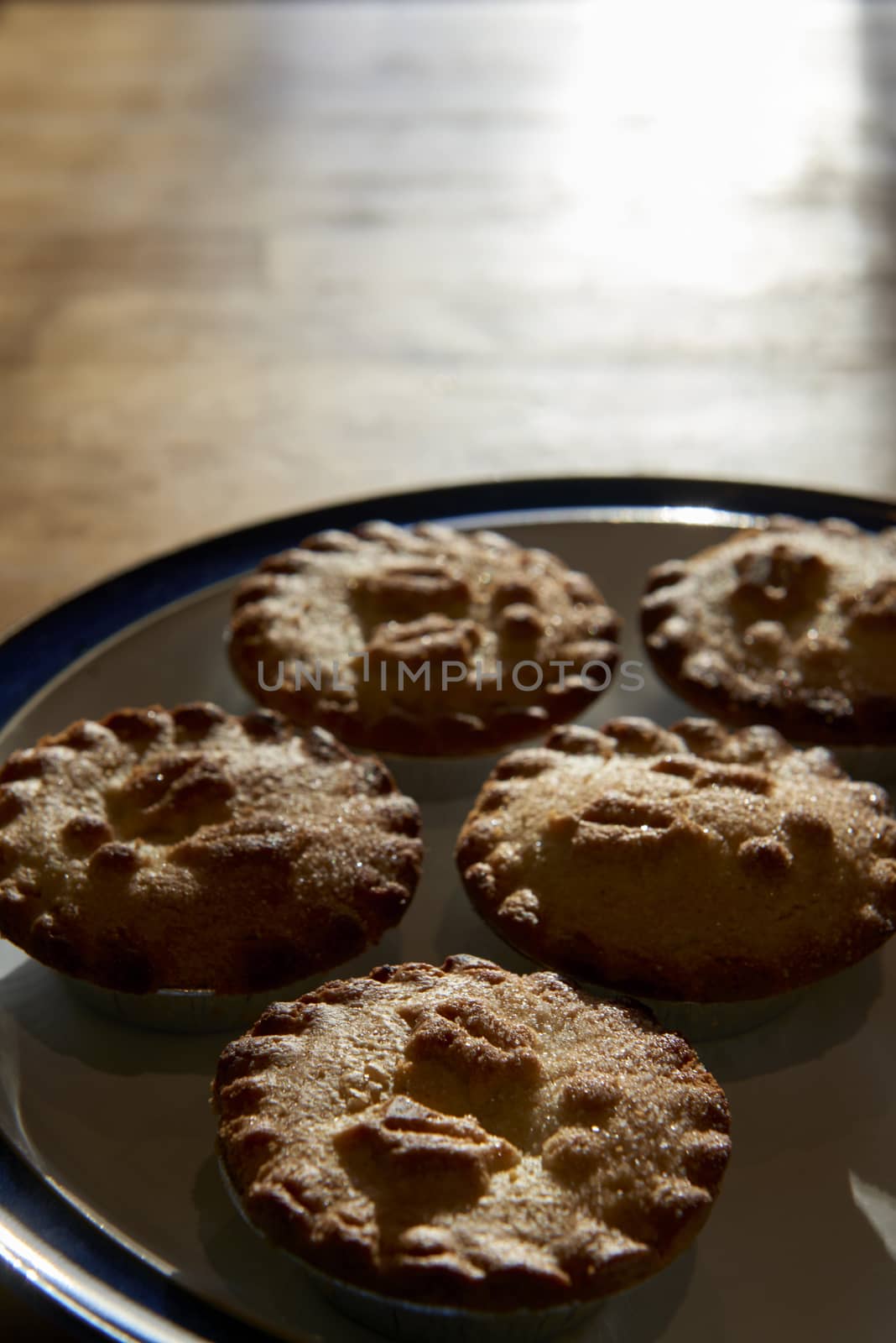 Plate of mince pies shot against the light on a wooden table