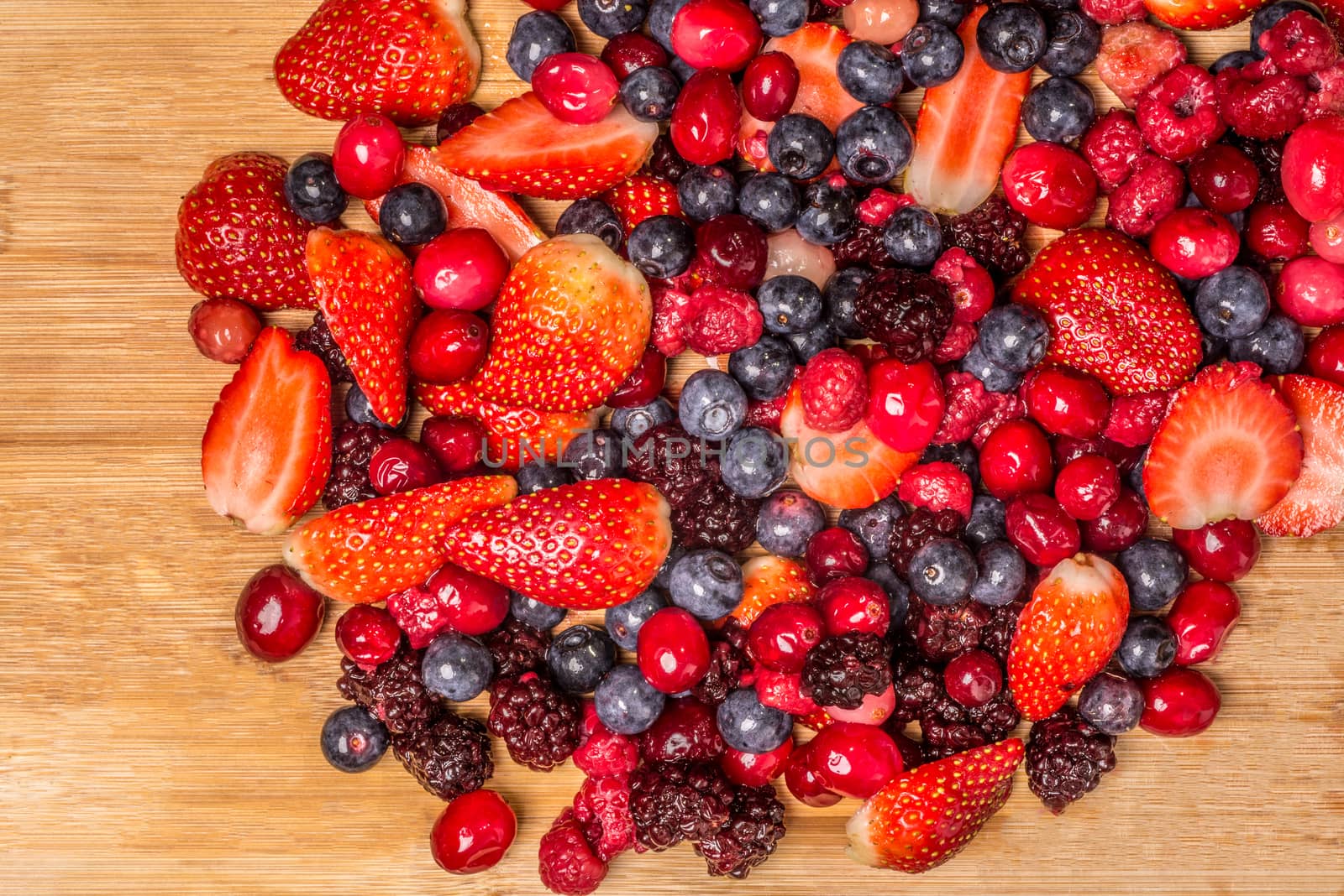 Mixed berries viewed from above as they lie spread out on a bamboo cutting board.