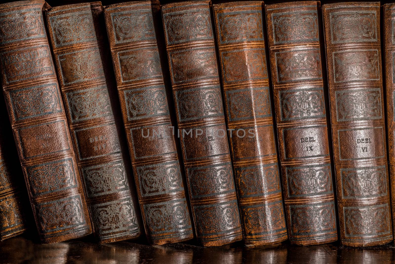 Old Books in a book shelf, stacked one next to the other in an upright position.