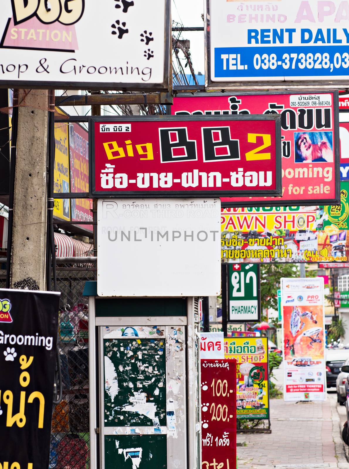 PATTAYA, THAILAND - NOVEMBER 27, 2014: An abundance of shop signs along the sidewalk of Pattaya Third Road in Pattaya City, Thailand makes navigating the road a challenge for pedestrians.