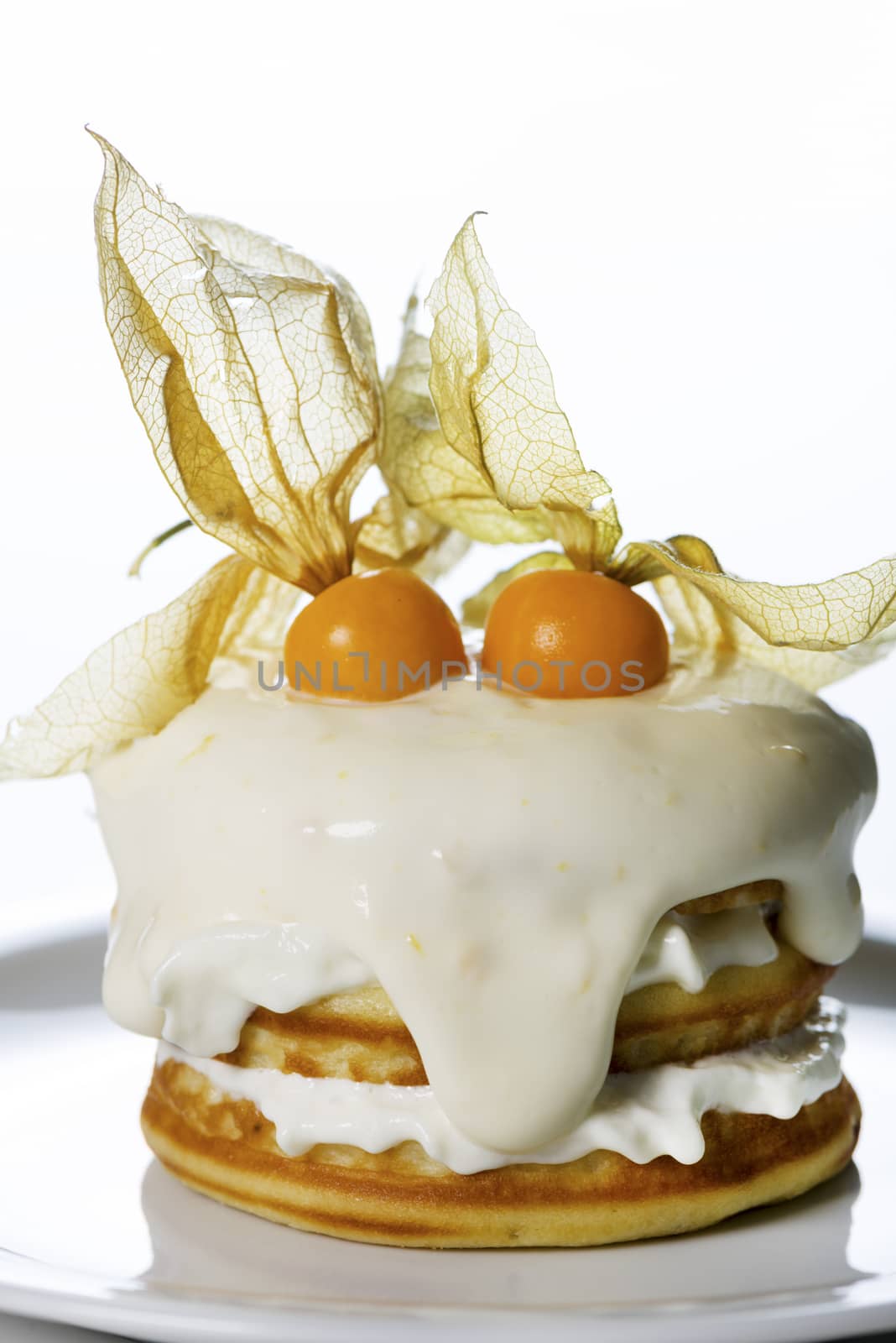 a stack of pancakes with cream and decorated with physalis on white background