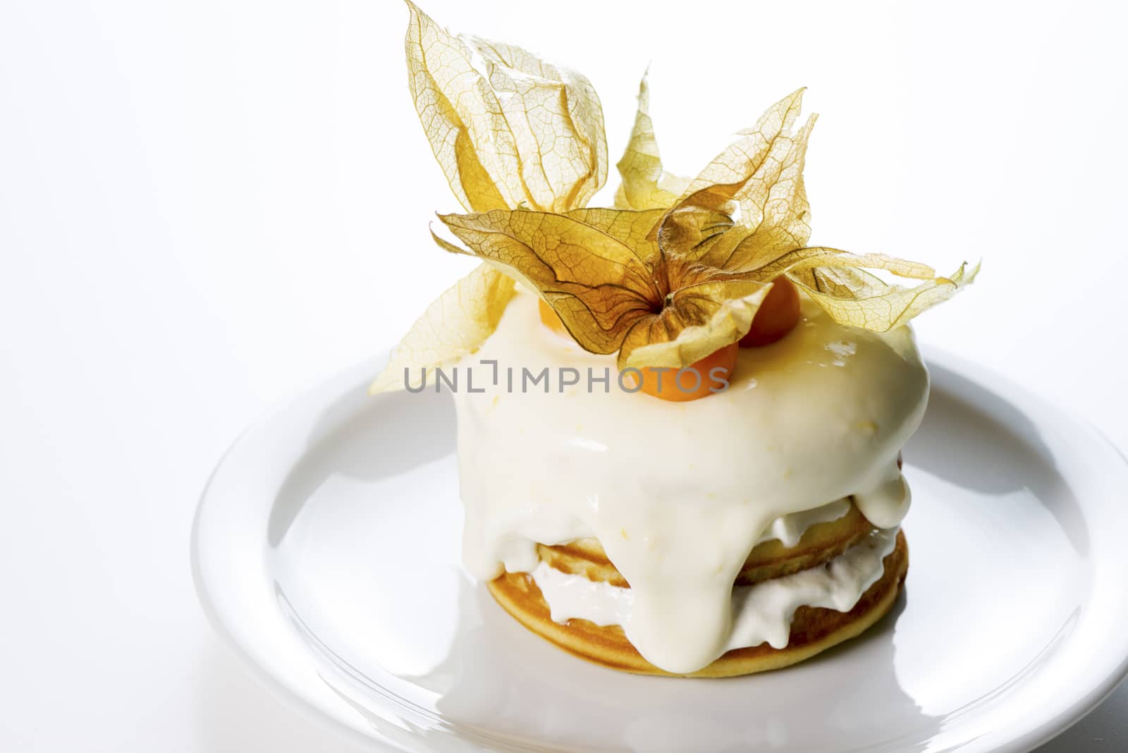 a stack of pancakes with cream and decorated with physalis on white background