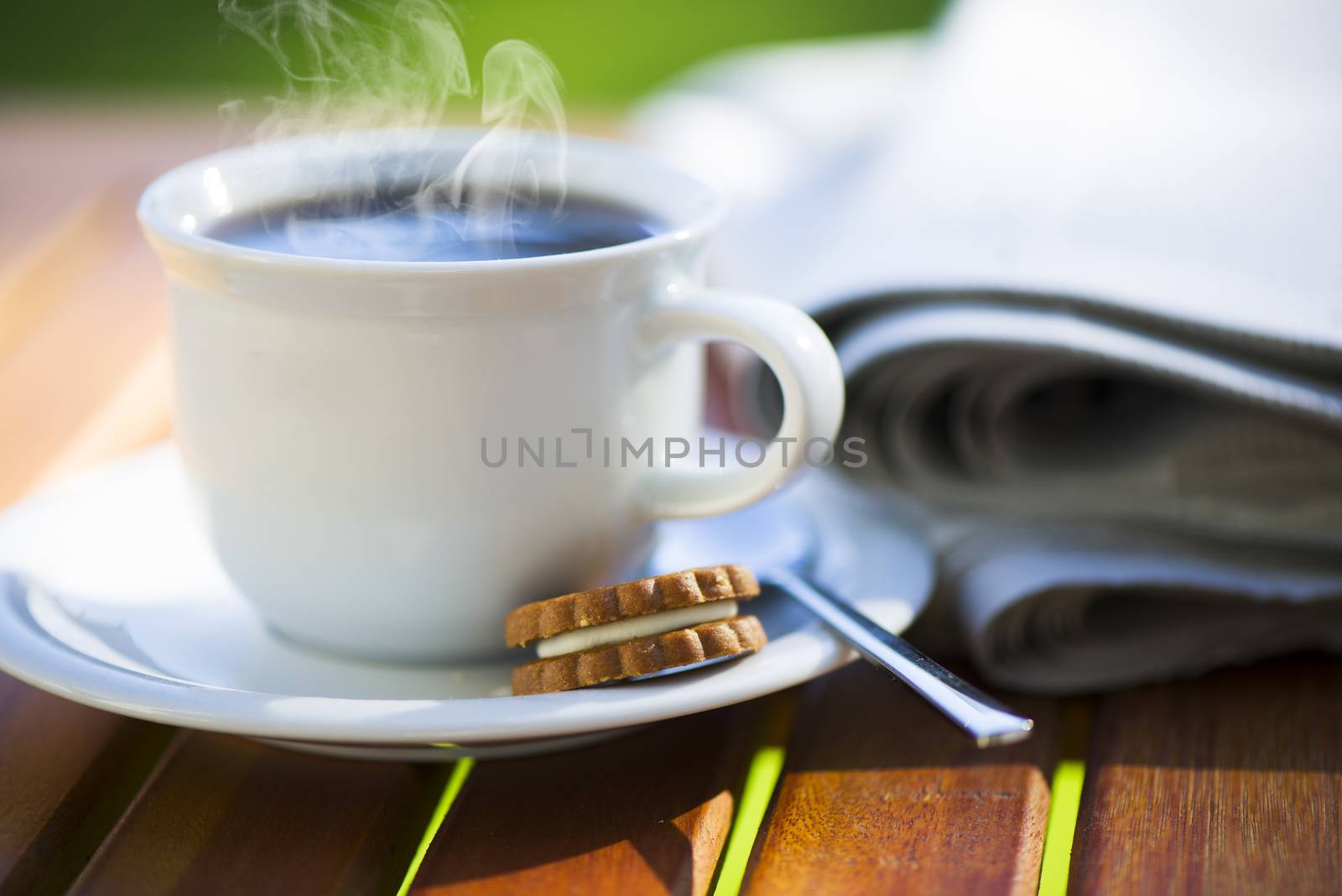 a white cup of hot coffee on wood table with newspaper and area for your text