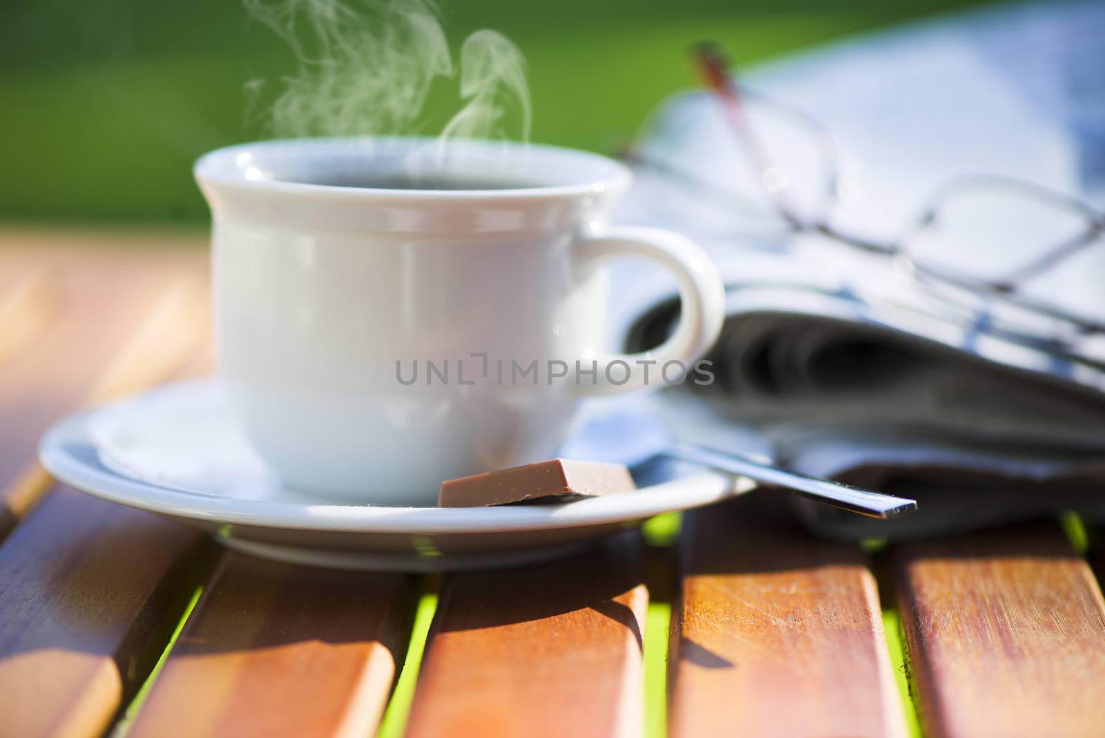 a white cup of hot coffee on wood table with newspaper and area for your text