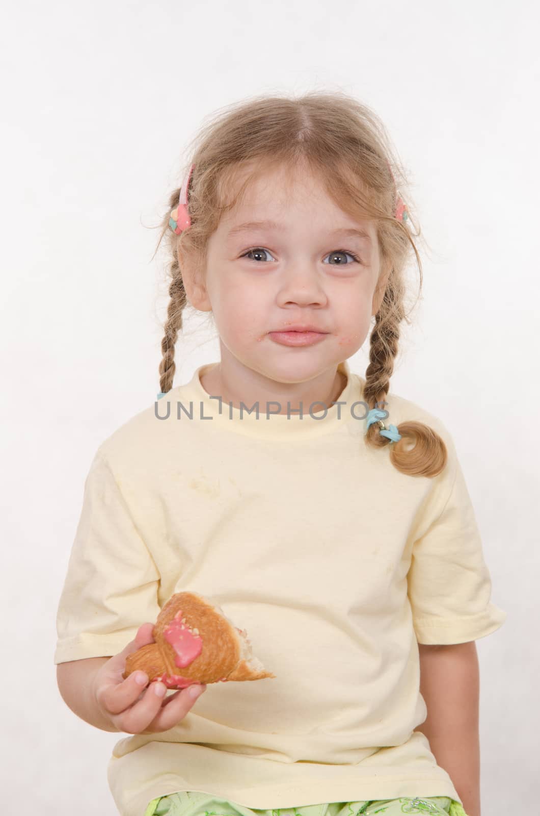 Three year old girl with pigtails and funny enthusiastically eating a bun