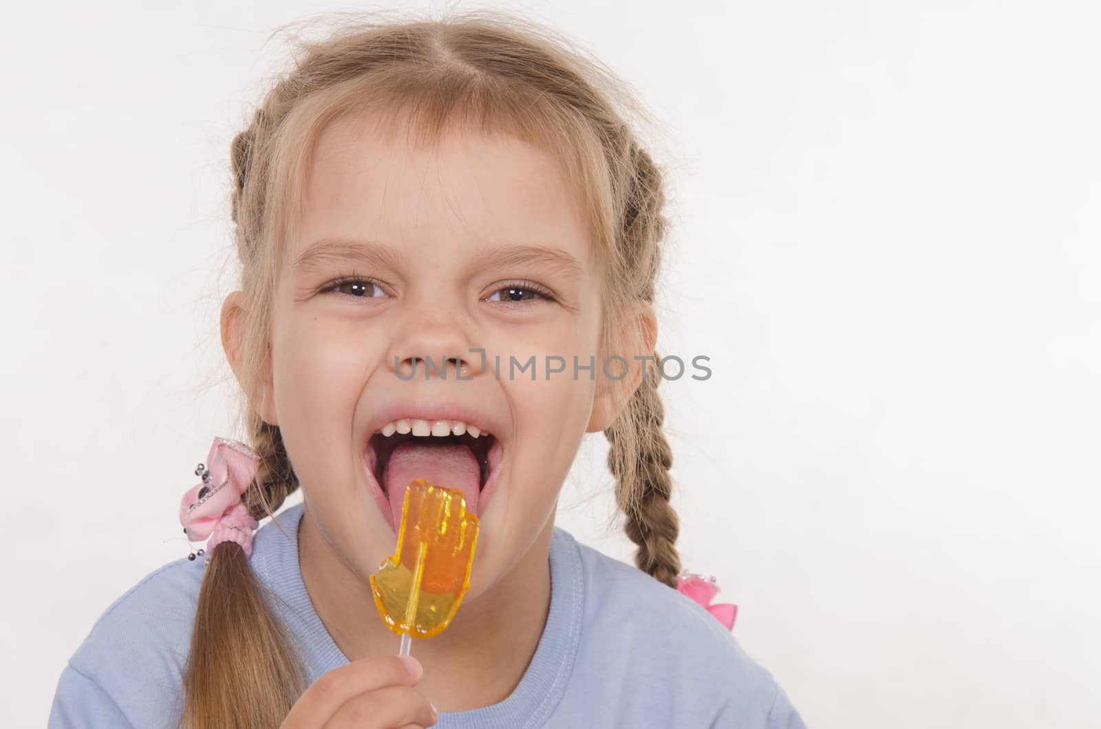 the five-year old girl enthusiastically eats candy